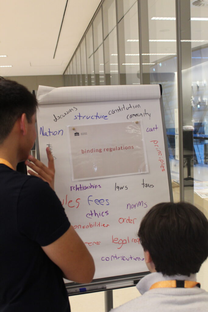 Zwei junge Menschen stehen vor einer Flipchart und dürften den Text darauf durchlesen.